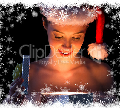 Pretty woman in santa outfit opening a gift smiling at it