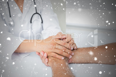 Close up mid section of a doctor holding patients hands