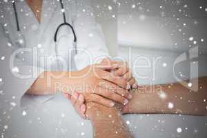 Close up mid section of a doctor holding patients hands