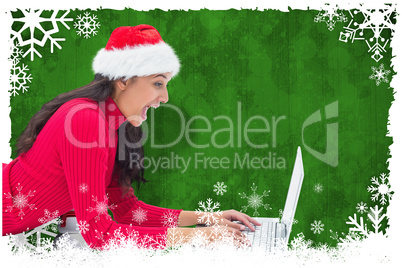 Composite image of festive brunette pointing at laptop