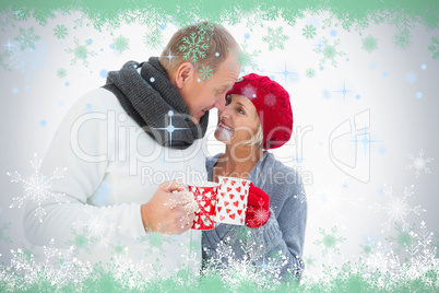 Happy mature couple in winter clothes holding mugs