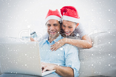 Smiling couple in santa hats shopping online with laptop