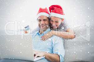 Smiling couple in santa hats shopping online with laptop