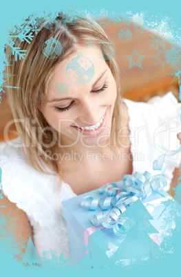 Delighted young woman holding a present sitting on the floor