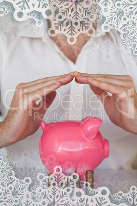 Casual businessman sheltering piggy bank and coins