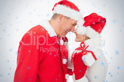 Festive older couple smiling at each other and holding gift