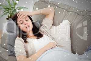 Indisposed woman feeling her temperature while resting on the so