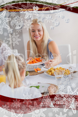 Mother handing carrots to daughter at dinner