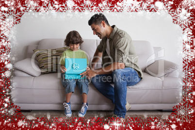 Father and son with gift box sitting in living room