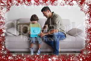 Father and son with gift box sitting in living room