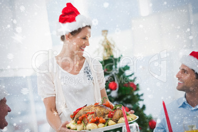 Cheerful woman wearing santa hat and bringing a roast chicken