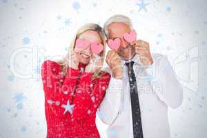 Silly couple holding hearts over their eyes