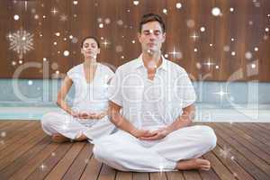 Peaceful couple in white sitting in lotus pose together