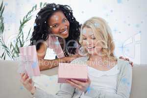 Woman opens a box containing a present and her friend smiles