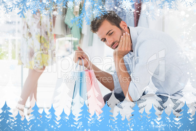 Bored man with shopping bags while woman by clothes rack