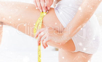 Composite image of toned woman measuring her thigh