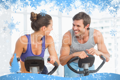 Smiling young couple working out at spinning class