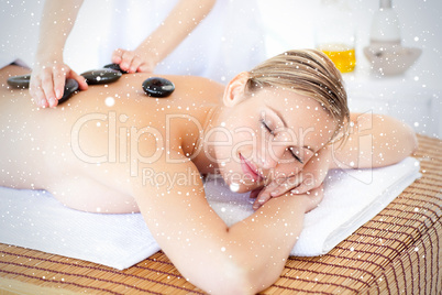 Pretty young woman receiving a massage with hot stone