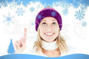 Composite image of bright woman with a colorful hat pointing upw