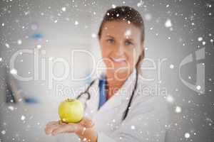 Doctor with stethoscope holding an apple looking at the camera