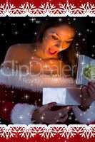 Composite image of pretty brunette in santa outfit opening gift