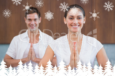 Smiling couple in white sitting in lotus pose with hands together
