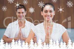 Smiling couple in white sitting in lotus pose with hands together