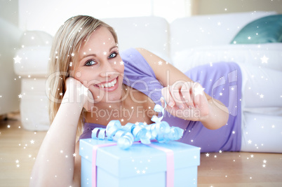 Composite image of delighted blond woman holding a present lying