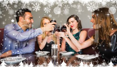 Composite image of happy friends drinking red wine in a bar