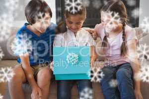 Composite image of happy kids with gift box in living room