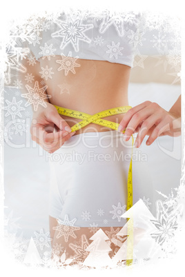 Composite image of toned woman measuring her waist