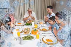 Family of six saying grace before meal at dining table