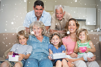 Composite image of siblings holding gifts with family in living