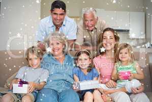 Composite image of siblings holding gifts with family in living