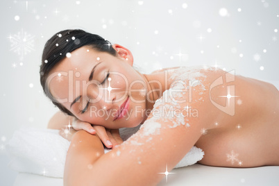 Peaceful brunette lying with salt scrub on shoulders