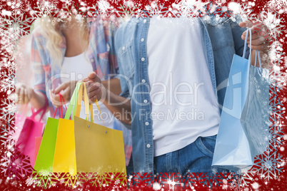 Composite image of cute young couple holding shopping bags