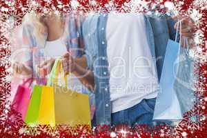 Composite image of cute young couple holding shopping bags