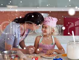 Composite image of nice mother and her daughter baking in a kitc