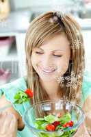 Young woman eating a salad in the kitchen