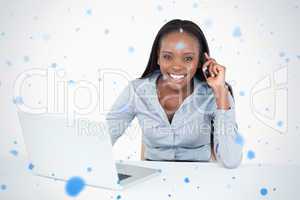 Businesswoman making a phone call while using a laptop