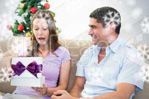Composite image of surprised woman opening christmas present