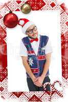 Composite image of geeky hipster in santa hat