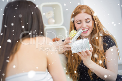 Composite image of young woman surprising blond friend with a gi