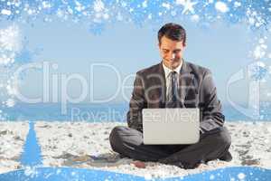 Young businessman with legs crossed typing on his laptop