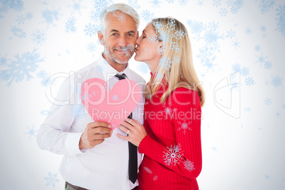 Handsome man holding paper heart getting a kiss from wife