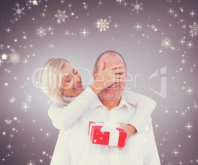 Composite image of woman surprising man with gift