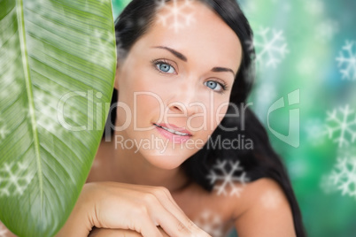 Beautiful nude brunette smiling at camera with green leaf