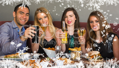 Composite image of friends having dinner together smiling at cam