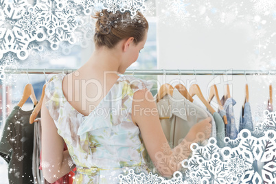 Female customer selecting clothes at clothing rack in store