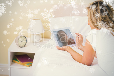 Thoughtful woman using a tablet pc lying on her bed